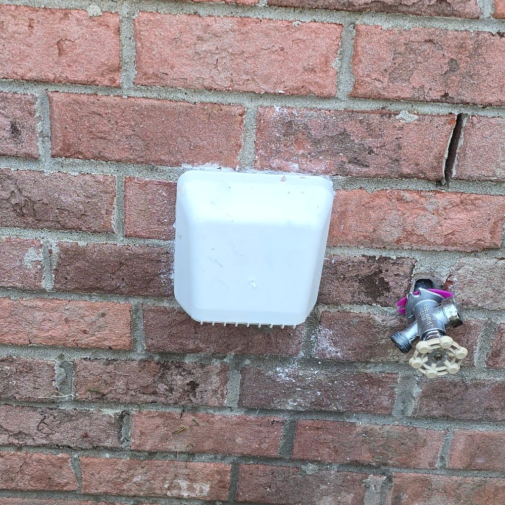 A new white dryer vent hood installed on the same brick wall, clear of obstructions