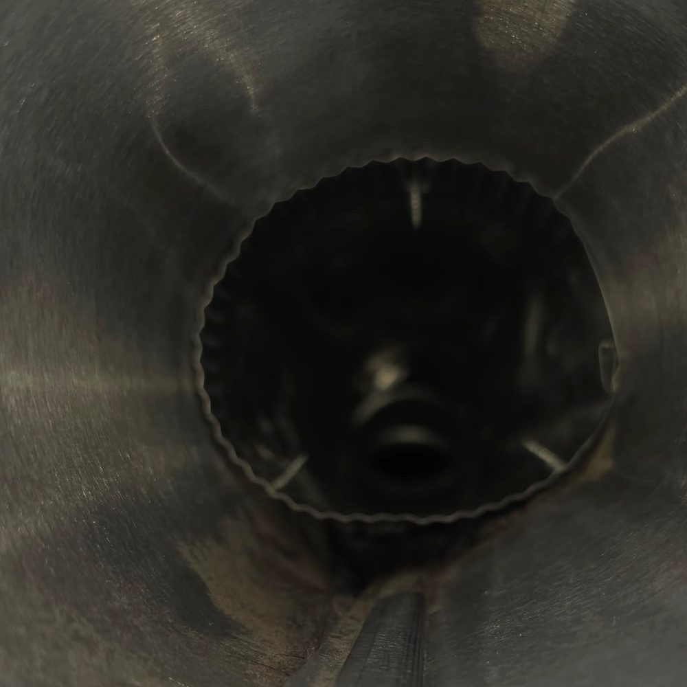 The same dryer vent after cleaning, bare metal duct wall with a clear opening