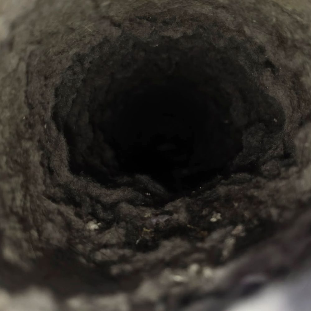 Inside a dryer vent before cleaning, the duct wall thick with matted lint